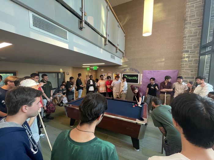 students gathered around pool table playing