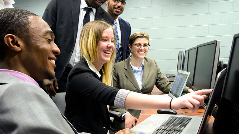 Several students looking and pointing at computer screen