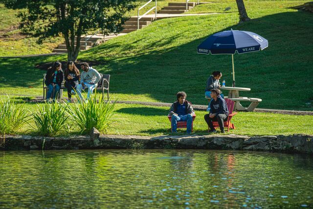 students sitting by pond