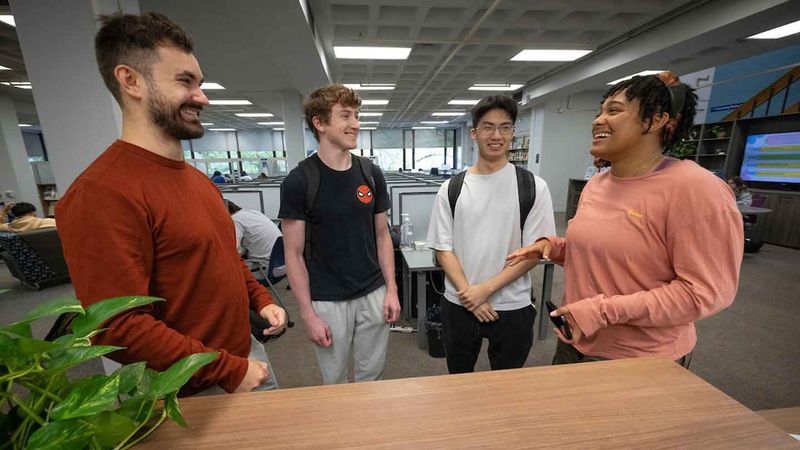 four students talking in the library