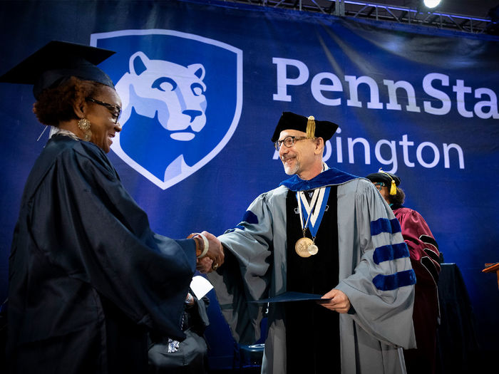 Interim Chancellor Andrew August presents a Penn State Abington student with her diploma
