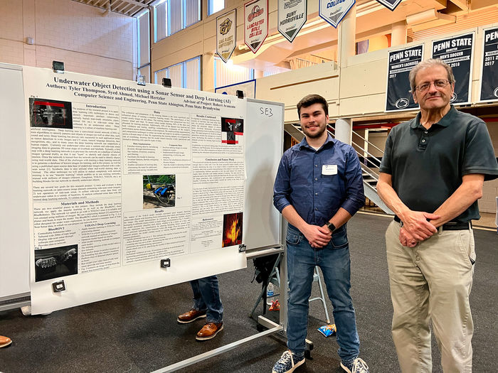 Student and professor stand next to research poster