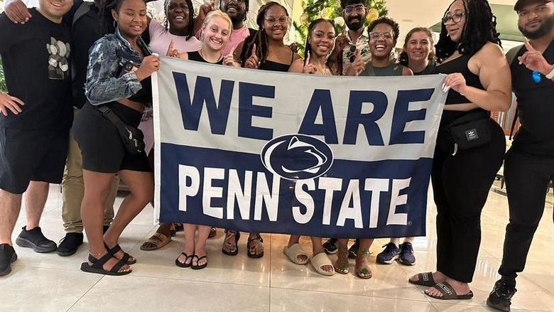 A group of people posing with a We Are Penn State sign