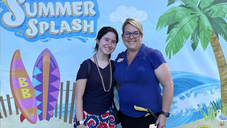 Two women standing in front of a Sesame Place sign