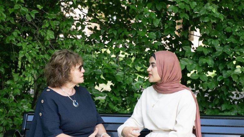 Two women sitting on a bench and talking