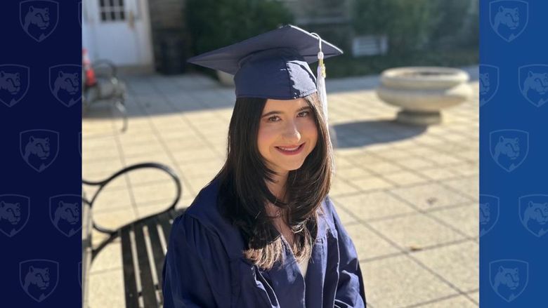 Student in cap and gown sitting outside