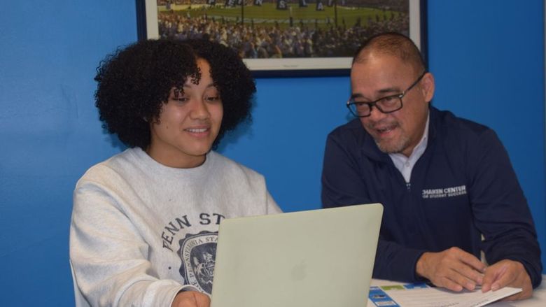 Student and staff member looking at laptop computer