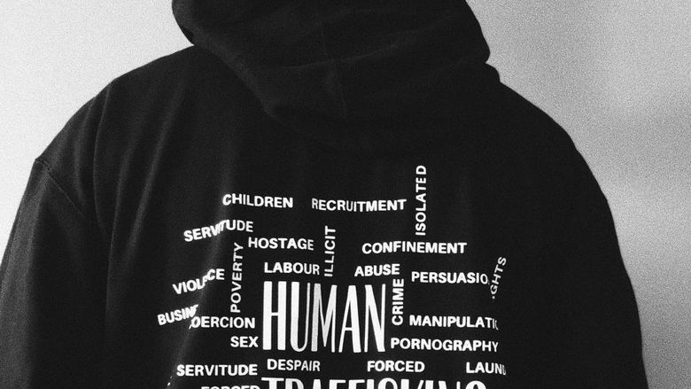 Man with back to camera and words on his hoodies related to human trafficking