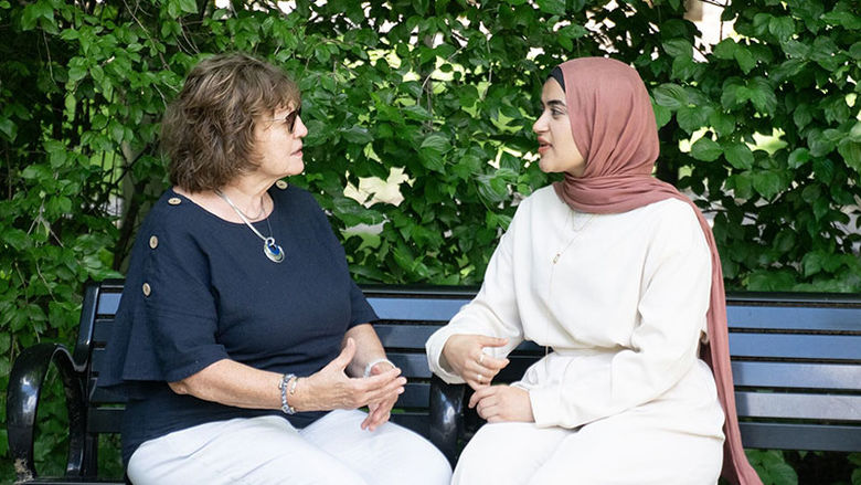 Two women sitting on a bench talking at Penn State Abington near Philadelphia