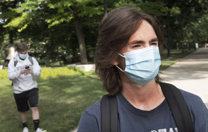 Two students wear walk across campus at University Park wearing face masks.