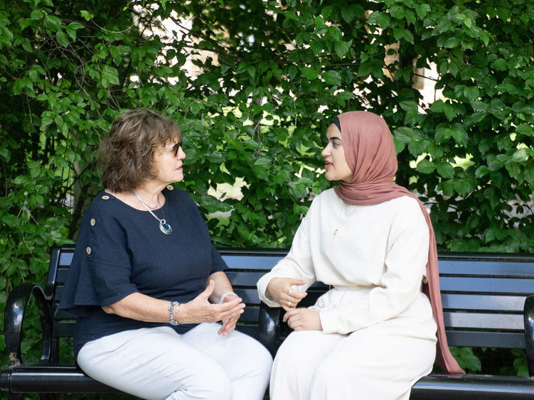 Two women sitting on a bench and talking